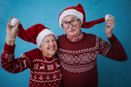 Portrait of happy senior couple with Santa Claus hats in studio.