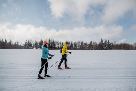 Senior couple skiing together in the middle of forestの写真素材