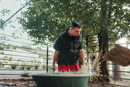 Caretaker with down syndrome in zoo cleaning animal enclosure. Concept of integration people with...