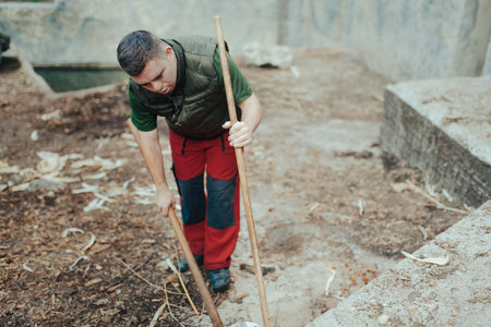 Caretaker with down syndrome in zoo cleaning animal enclosure. Concept of integration people with disabilities into society.の写真素材