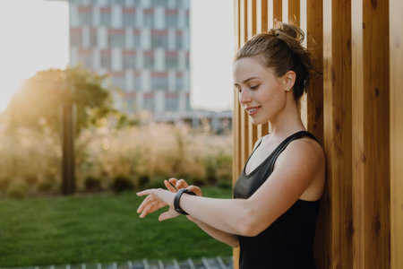 Young woman checking smartwatch in city, preparing for run, healthy lifestyle and sport concept.