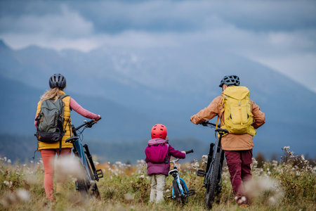 Rear view of family with little child at bicycles, in the middle of autumn nature.Concept of a healthy lifestyle.の写真素材