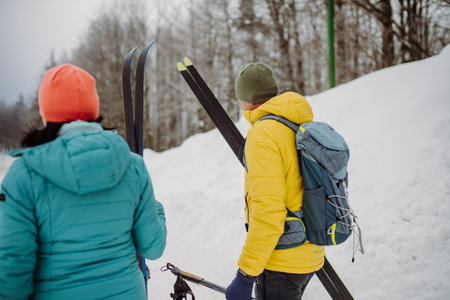 Senior couple crossing forest with skis in hands.の写真素材