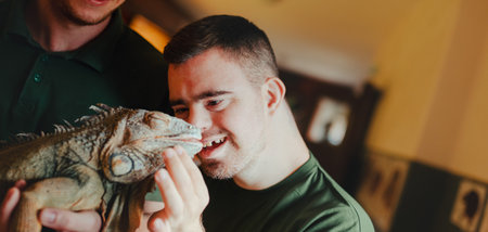 Caretaker with down syndrome taking care of animals in zoo, stroking iguana. Concept of integration...