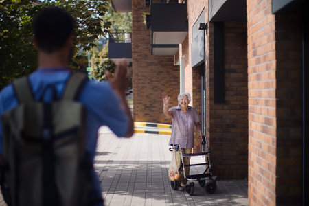 Caregiver saying goodbye his senior woman client at nursing home.