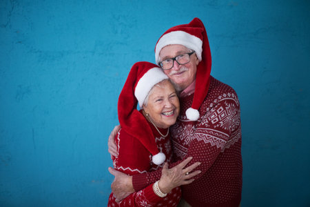 Portrait of happy senior couple in Christmas sweaters hugging, studio shooting.の写真素材