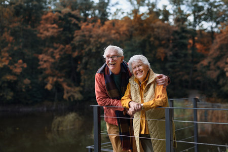 Happy senior couple at autumn walk near the lake, having break.