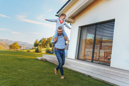 Father with his little daughter having fun in their backyard during sunny autumn day.の写真素材