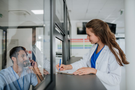 Young doctor talking at hospital reception with her colleague.の写真素材
