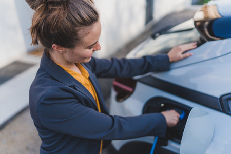 Young woman charging her electric car in home, sustainable and economic transportation concept.の写真素材