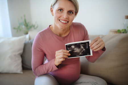 Pregnant woman showing ultrasound photo of her baby.