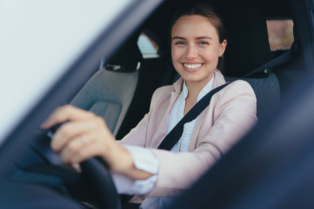 Excited young woman sitting in her car, prepared for driving.の写真素材