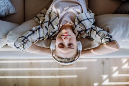 Top view of young woman relaxing with headphones, listening music.