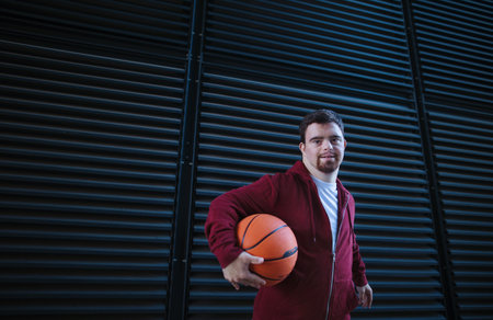 Portrait of young man with down syndrom holding basketball ball.の写真素材