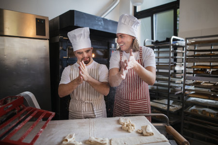 Man with down syndrom helping prepair bread in bakery with his colleague. Concept of integration...