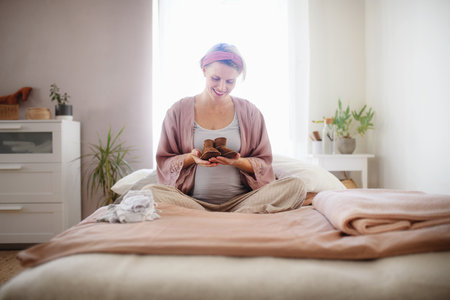 Happy pregnant woman holding little shoes for her baby.の写真素材
