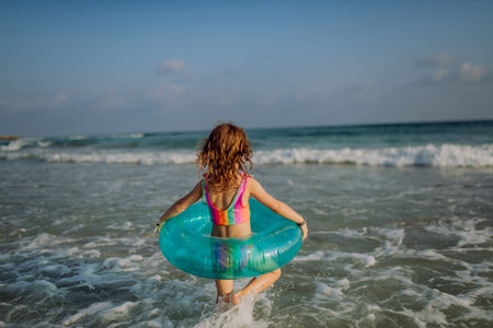 Rear view of little girl enjoying sea.の写真素材
