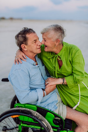 Senior man on wheelchair enjoying together time with his wife at sea.の写真素材