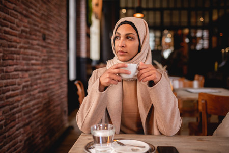 Young muslim woman enjoying cup of coffe in cafe.の写真素材