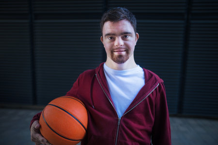 Portrait of young man with down syndrom holding basketball ball.の写真素材