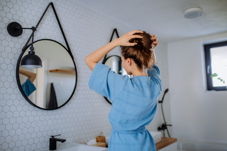 Young woman taking care of her hair, morning beauty routine concept.の写真素材