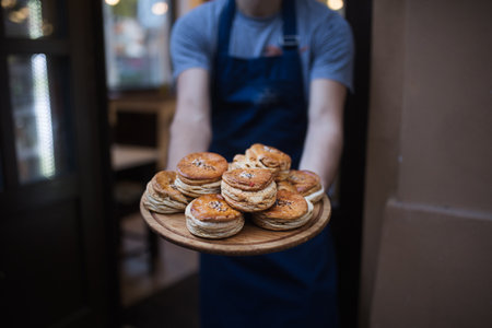 Close-up of man with apron holding fresh pastries.の写真素材