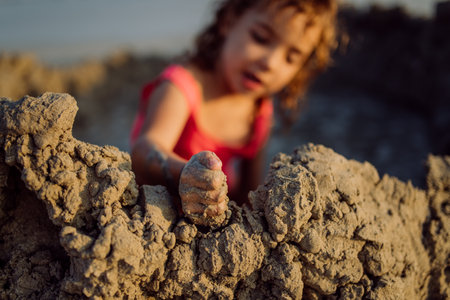 Little girl playing on the beach, digging hole in sand.の写真素材