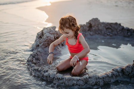 Little girl playing on the beach, digging hole in sand.の写真素材