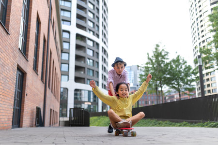 Happy children enjoying skateboard ride and going down the hill, looking at camera.の写真素材