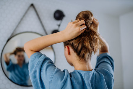 Young woman taking care of her hair, morning beauty routine concept.の写真素材