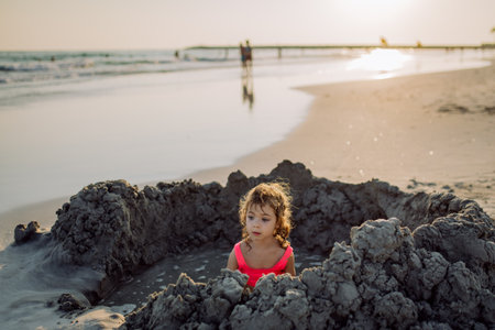 Little girl playing on the beach, digging hole in sand.の写真素材