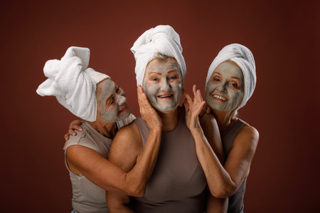 Portrait of happy senior friends with face-mask, selfcare and skin routine concept.の写真素材