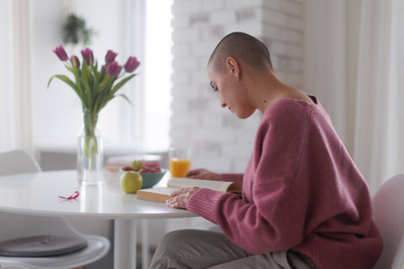 Young woman with cancer reading book, cancer awareness concept.の写真素材