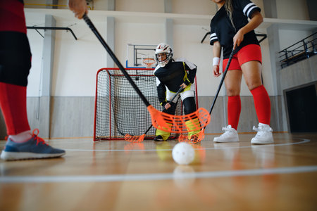 Multigenerational woman floorball team playing together in a gym.