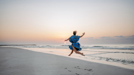 Young woman enjoying time at sea, jumping.の写真素材