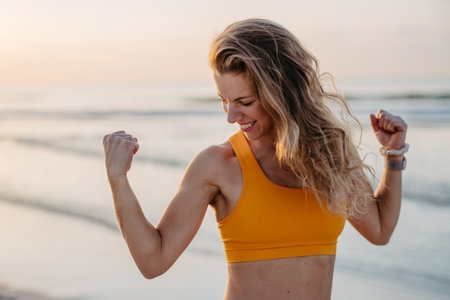 Young sportive woman showing her muscles at beach.