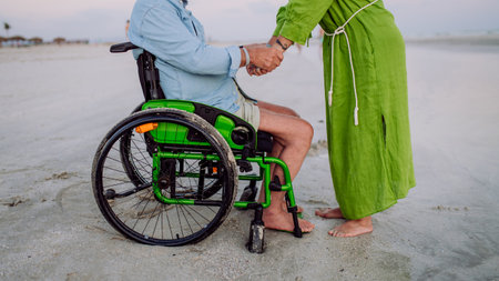 Senior man on wheelchair enjoying together time with his wife at sea, low section.の写真素材