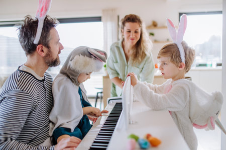 Happy family in easter costumes playing on the piano.の写真素材