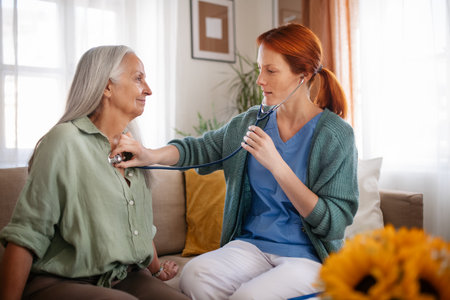 Nurse examining senior patient with stethoscope at her home.の写真素材