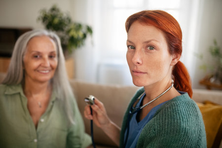 Nurse examining senior patient with stethoscope at her home.の写真素材