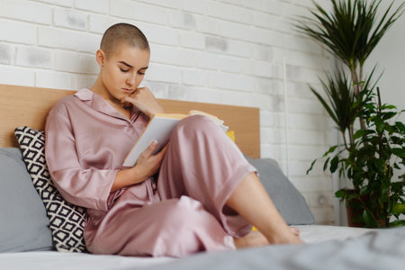 Young woman with cancer reading book, cancer awareness concept.の写真素材
