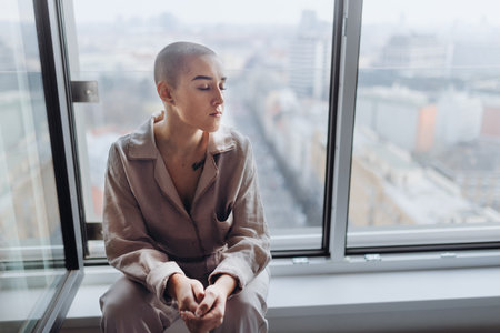 High angle view of young woman with cancer sitting in a window.の写真素材