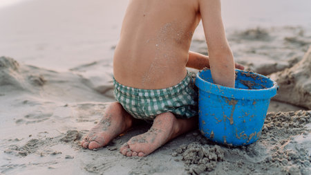 Little boy playing on the beach, building sand castle.の写真素材