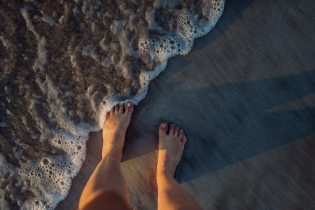 Woman walking on a beach during sunset, close-up of feet.