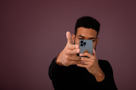 Portrait of young multiracial man with smartphone in studio.の写真素材