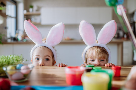 Little siblings enjoying easter time together in home.の写真素材
