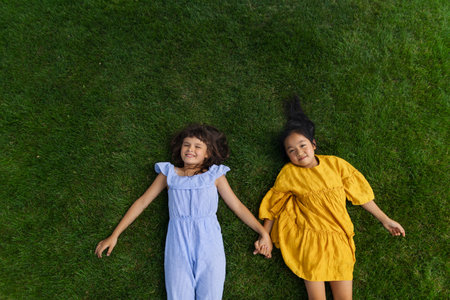 Happy friends lying in the grass, holding each other hands and having fun. Top view.の写真素材