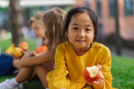 Happy children eating fresh apples in park.の写真素材