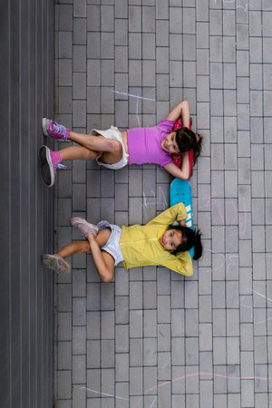 Happy friends lying in sidewalk, resting after skateboarding, having fun. Top view.の写真素材