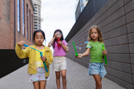Happy three friends enjoying summer time in the city, blowing bubbles.の写真素材